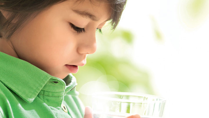 A boy looking into a glass of clean water