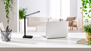 A table lamp on a desk aimed at paper and pen