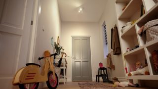 Bright entryway with LED recessed lighting illuminating shelves, toys, and a children's balance bike.