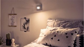 Stylish bedroom with adjustable LED spotlight creating cosy ambiance, illuminating geometric bedding and minimalist decor.